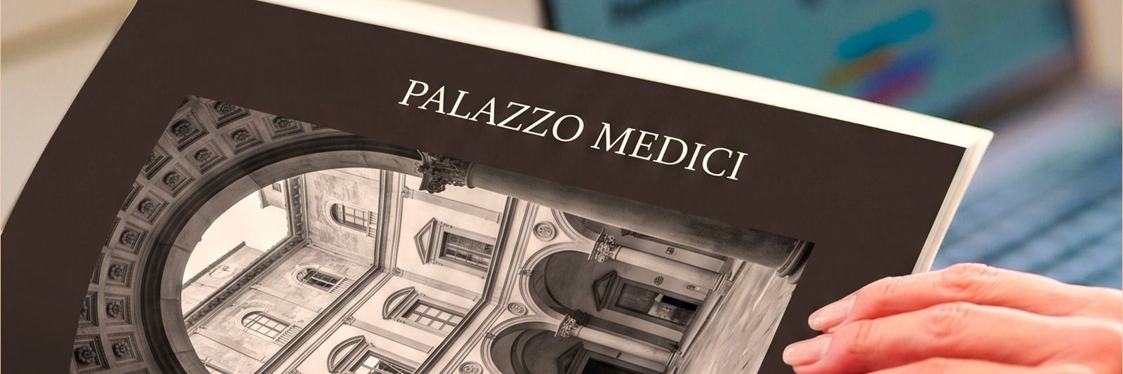 Un libro d'arte sul Palazzo Medici sfogliato accanto a un portatile: lo studio della borsa Milva Tinarel